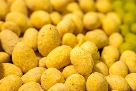 A detailed close-up of two varieties of peanuts, one with a green spice. Stock Photos