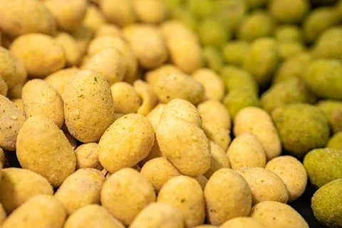 A detailed close-up of two varieties of peanuts, one with a green spice. Stock Photos