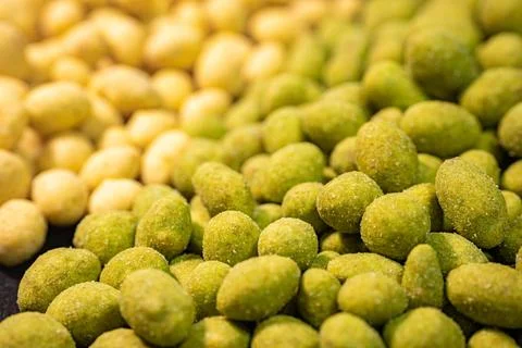 A detailed close-up of two varieties of peanuts, one with a green spice. Stock Photos
