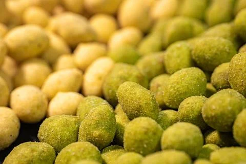 A detailed close-up of two varieties of peanuts, one with a green spice. Stock Photos