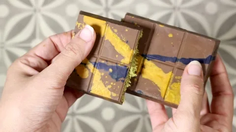 A detailed close up of a woman's hands breaking open the viral Dubai chocolate w 스톡 동영상 332114424