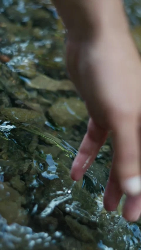 A detailed closeup of a hand gently touching the flowing water, embracing the Stock Footage 304735843