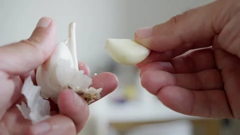 A detailed closeup of hands skillfully peeling a garlic bulb, ideal for various Stock Footage 312742270