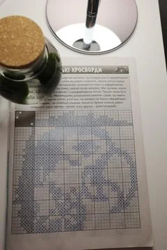 A detailed cross-stitch pattern printed on paper rests on a white surface Stock Photos