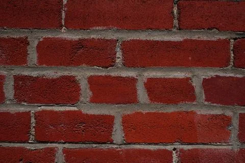 A detailed full-frame close-up view of a red brick wall showcasing the rough Stock-Fotos