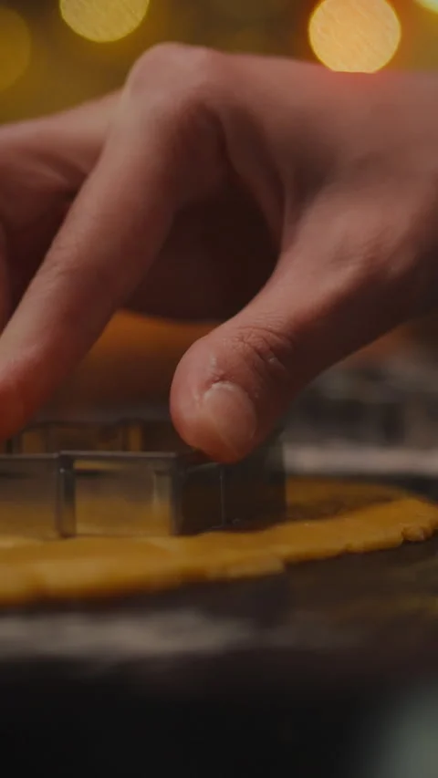 Detailed hands using a cookie cutter on dough for festive baking activity at Stock Footage 331569783