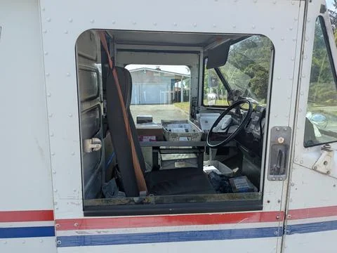 A detailed interior shot through the window of a parked white mail truck Stock Photos
