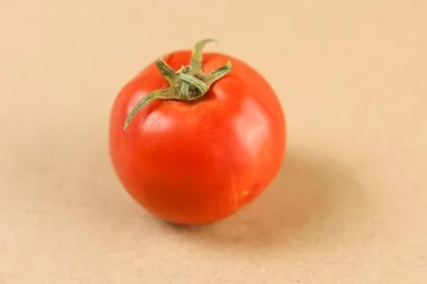 A detailed macro close-up of a single red tomato crowned with its vibrant green Stock Photos