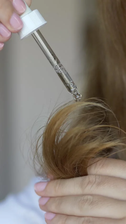 Detailed macro of dropper pipette dispensing serum on hair in luxury haircare Stock-Footage 336381253