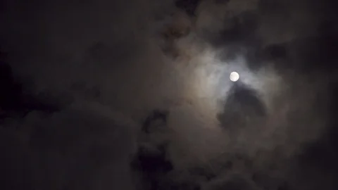 Detailed moon texture shines through broken clouds in the night sky, 4K Stock Footage