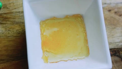 Detailed serving study of pouring amber caramel into a white square mold Stock Footage 342153993