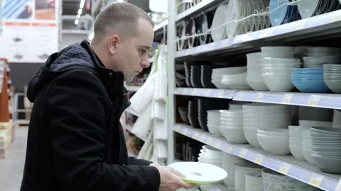 Detailed shopper evaluating dinnerware, scanning ceramic plates and comparing Stock Footage 312136605