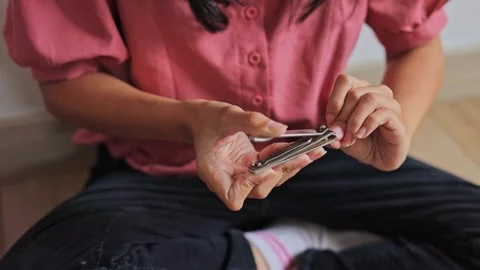 Detailed shot of hands using nail clippers for routine manicure and personal Stock Footage 345379584