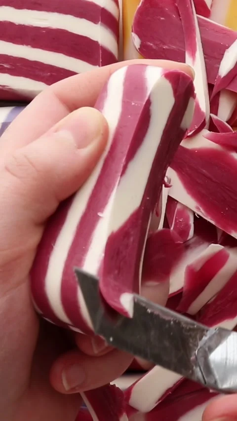 Detailed slicing of a red and white soap bar, with clean precision. The close-up Stockbeeldmateriaal 313753389