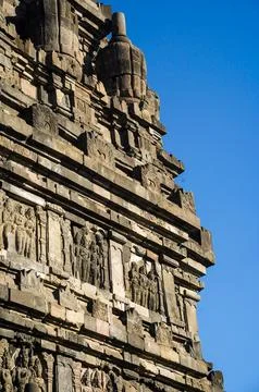 Detailed stone facade and upper tower of Prambanan Temple against a vivid b.. Photos