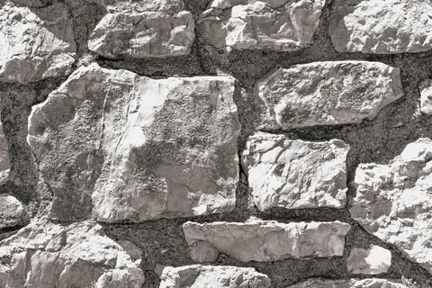 Detailed texture of light grey stone wall made of rough masonry blocks with.. Stock Photos