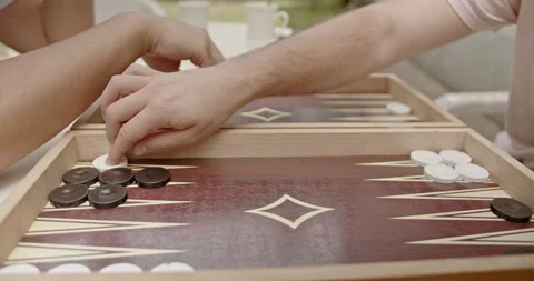 A detailed view of a backgammon game being played by two people outside. The Stock Footage 281577817
