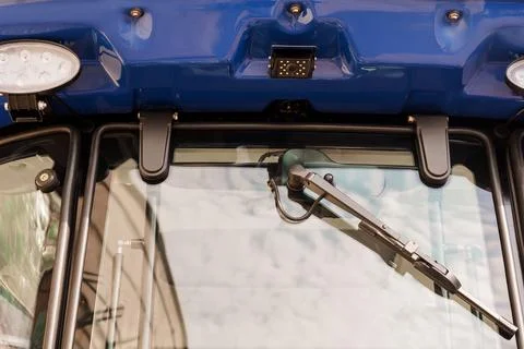 Detailed view of a blue tractor cab featuring a windshield wiper and sensor f Stock Photos