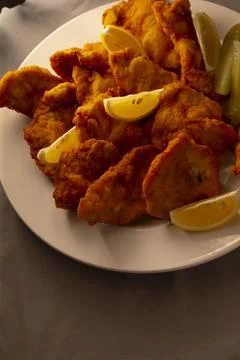 Detailed view of breaded cutlet garnished with lemon and pickle slices Stock Photos