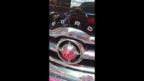A detailed view of a classic car, highlighting the emblem and logo, on display a Stock Footage 347009725