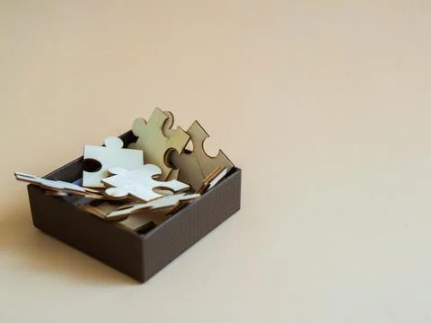 Detailed view of interlocking puzzle pieces inside brown box set against ne.. 스톡 사진