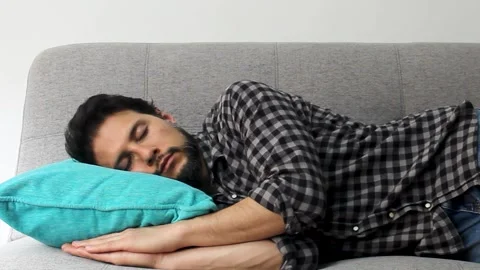 Detailed view of a latin man taking a deeply nap over a grey couch Stock Footage 340583450