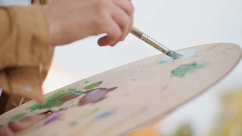 Detailed view of painter blending sky blue and green pigments outdoors. Captured Stock Footage 331261032