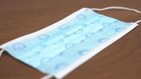 Detailed view of a patterned surgical mask on a wooden table Stock Footage 195518734