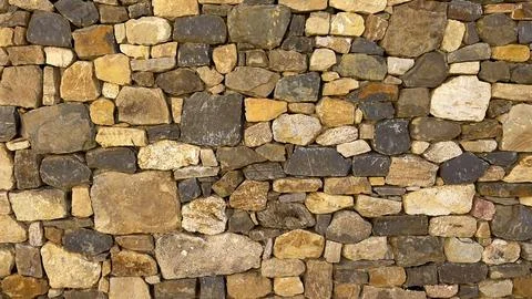 Detailed view of a rustic stone wall showcasing varied shapes and earthy tone Stock Photos