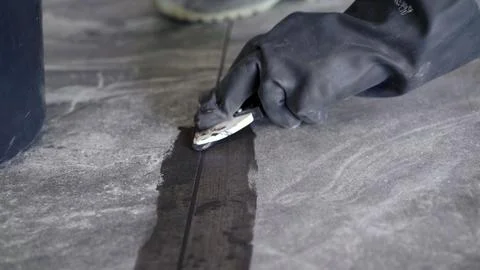 Detailed view of tiler's hand using squeegee tool to fill joints between tile Stock Photos