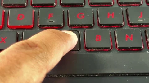 Detailed view of typing on "V" button laptop keyboard with red lighting, Stock Footage 336356873