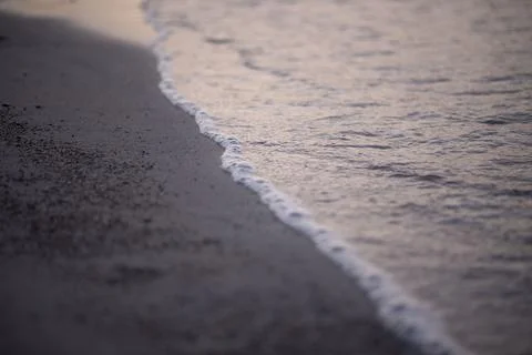 A detailed view of a wave rolling onto a sandy shore Stock Photos