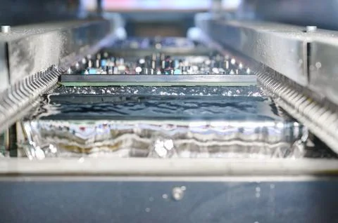Detailed view of wave soldering process during PCB tinning in molten solder bath Stock Photos