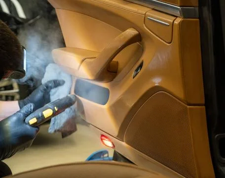 The detailing master cleans the car interior with a hot steam cleaner. Stock Photos