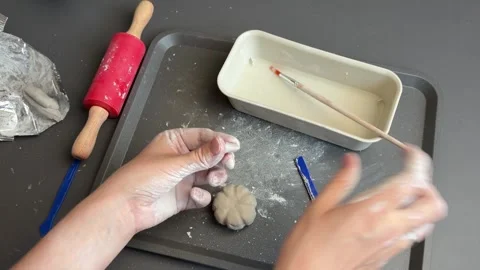 Detailing ridges on a miniature clay pumpkin with a fine brush handle Stock Footage 345720179