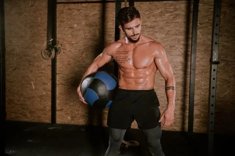 Details of a athletic guy using a cross fit ball to do his hard training workout Stock Photos