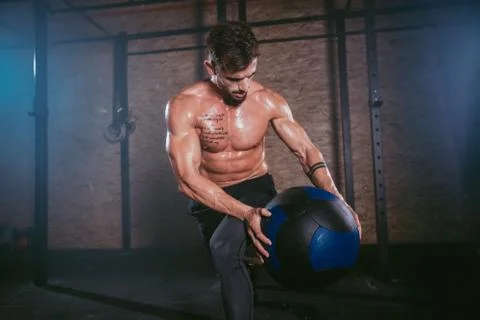 Details of a athletic guy using a cross fit ball to do his hard training workout Stock Photos