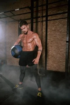 Details of a athletic guy using a cross fit ball to do his hard training workout Foto stock