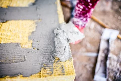 Details of construction  worker getting adhesive mortat on insulation board Stock Photos