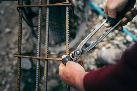 Details of construction worker - hands securing steel bars with wire rod Stock Photos