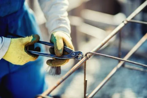 Details of construction workers hands securing steel bars with wire rod Stock Photos