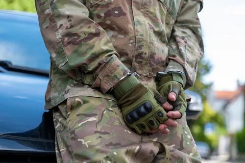 Detained serviceman with handcuffed hands beside a car 写真素材