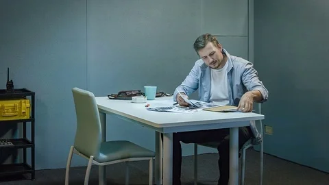 Detective with documents and coffee working at police office Vídeo Stock 69741252