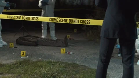 Detective inspecting area and taking notes in notebook at crime scene at night  Stock Footage 283866159