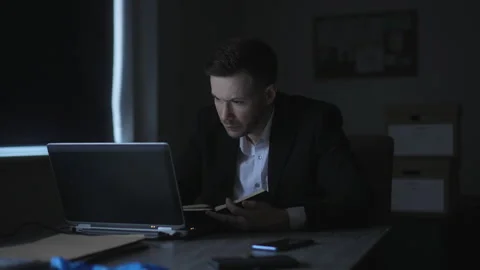 Detective Reviewing Case Notes And Laptop During Investigation Видео 330413608