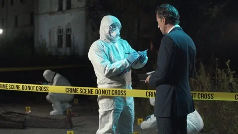 Detective talking to forensic expert and taking notes at crime scene at night Stock Footage 283866135