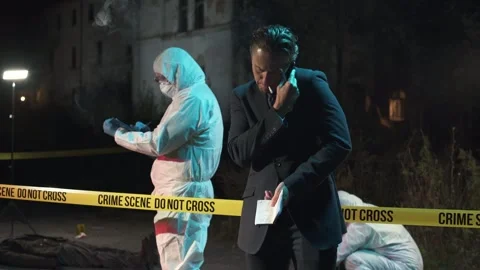 Detective talking on the phone and taking notes at crime scene at night Stock Footage 283866015