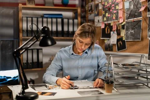 Detective working with documents at desk in her office Stock Photos