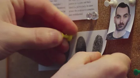 Detective's hands attach the fingerprint document to the suspect's photo Stock Footage 237944077