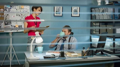 Detectives working in office, someone looking through window blinds behind them 스톡 동영상 70519261